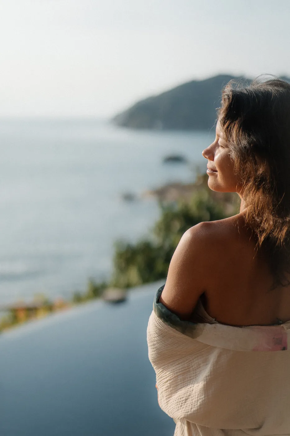 Mulher olhando o mar à beira da piscina do Vikasa