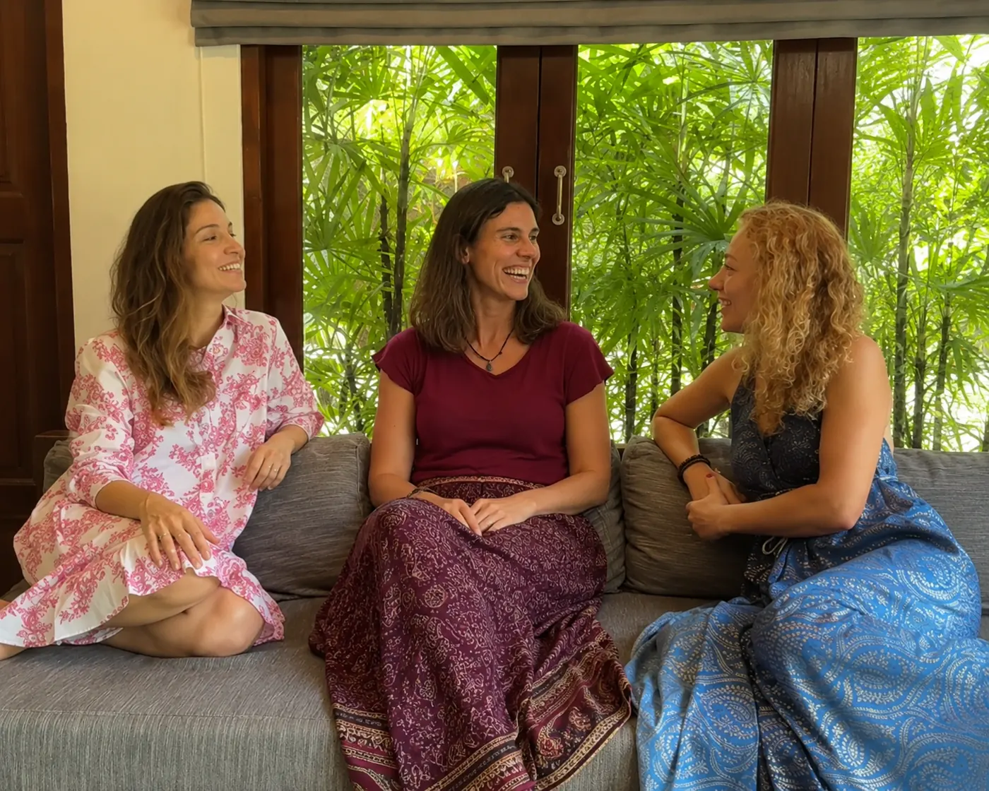Três mulheres conversando e sorrindo em um sofá
